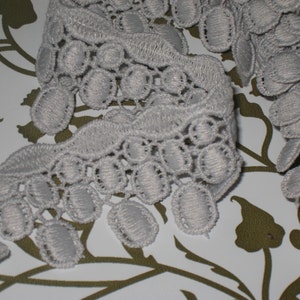 May include: Grey crocheted trim with a scalloped edge and a fringe of oval-shaped loops.