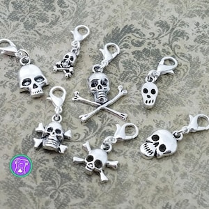 May include: Eight silver skull and crossbones charms with lobster clasps. The charms are perfect for adding a spooky touch to jewelry, bags, or keychains.