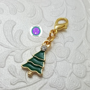 May include: Gold-tone Christmas tree charm with a green enamel finish and a clear rhinestone. The charm has a lobster clasp for attaching to a bag, keychain, or other items.