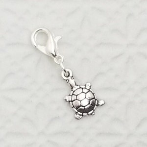 May include: Silver charm with a turtle design. The charm has a lobster clasp for attaching to a bracelet or necklace.