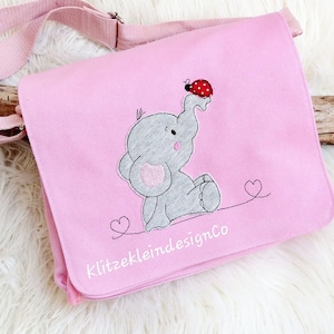 May include: Pink fabric messenger bag with an embroidered gray elephant and a red ladybug. The bag has a white embroidered heart and the text "KlitzekleindesignCo" on the front.