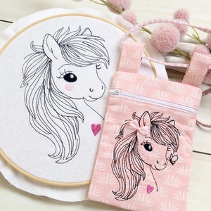 Könnte beinhalten: Ein weiß gesticktes Pferde-Design auf einem runden Reifen mit einem rosa gestickten Pferde-Design auf einer kleinen rosa Reißverschlusstasche mit einem weißen Riemen.