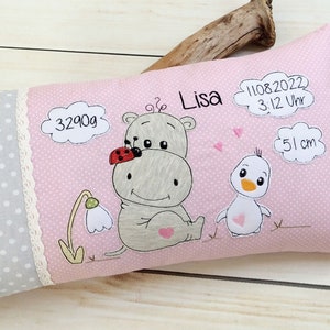 Op de afbeelding: Roze en grijze babykussen met een gestikte nijlpaard, lieveheersbeestje en kuiken. Het kussen heeft ook de tekst "Lisa", "3290g", "11.08.2022 3:12 Uhr" en "51 cm".