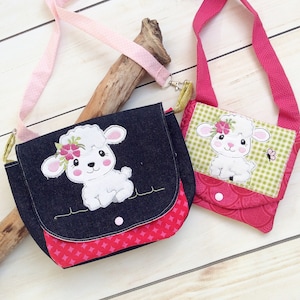 May include: Two small bags with pink straps and a lamb applique. The larger bag is made of denim and has a red and white patterned flap. The smaller bag is made of a green and white patterned fabric with a red and white patterned flap.