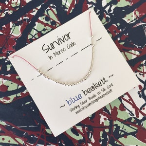 Puede incluir: Una tarjeta blanca con el texto "Survivor in Morse Code" y una pulsera de cuentas de plata. La tarjeta también incluye el texto "~ blue beckett ~ Sterling Silver Beads on Silk Cord www.etsy.com/shop/bluebeckett".