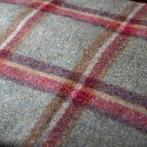 May include: Close-up of a green, brown, and red plaid fabric. The fabric has a soft, fuzzy texture.