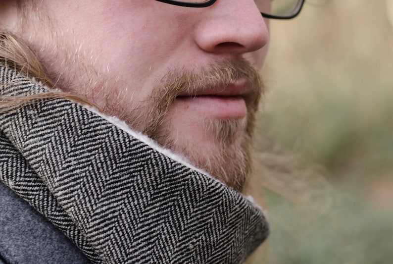 May include: Close-up of a man's face with a beard and a black and white patterned scarf around his neck.