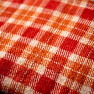 May include: Close-up of a red and white plaid fabric with a woven texture.