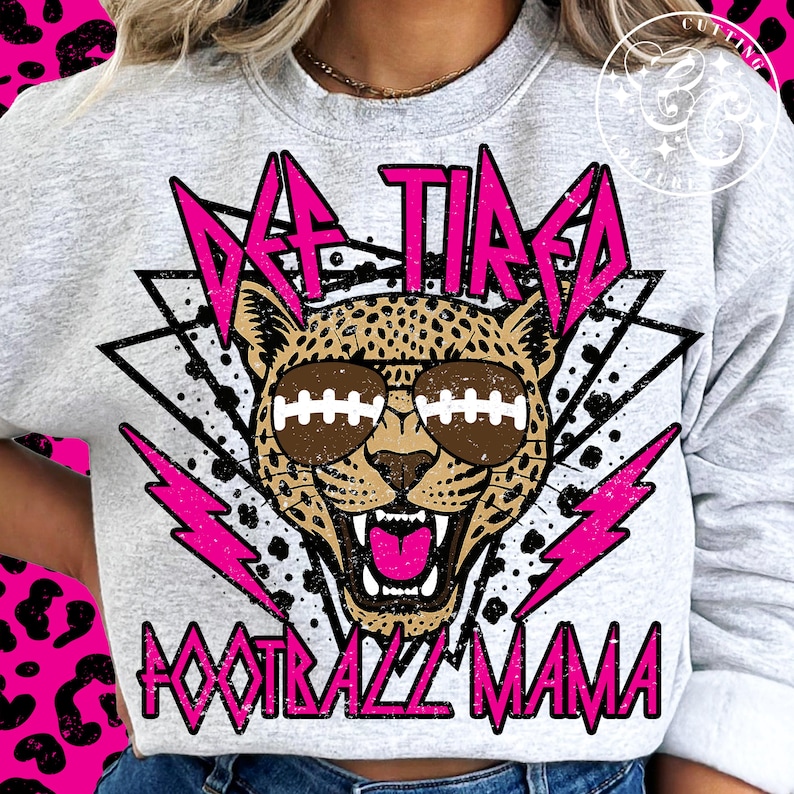 May include: A gray sweatshirt with a pink graphic design featuring a cheetah wearing sunglasses with footballs on the lenses. The graphic also includes the text "DEF TIRED FOOTBALL MAMA" in pink.