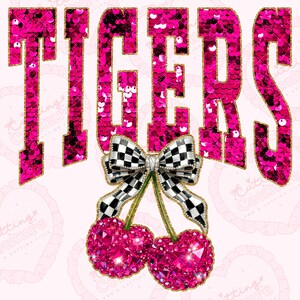 May include: A pink graphic design with the word "TIGERS" in a sequined font with gold trim. Below the word is a bow with a black and white checkered pattern and two pink jeweled cherries. The background is light pink.