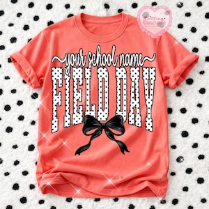 Peut inclure: T-shirt corail avec le texte "your school name" au-dessus de "FIELD DAY" dans un motif à pois blancs. Un nœud noir est centré en dessous du texte. Le t-shirt a des manches retroussées.