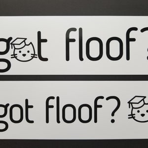 May include: Two white signs with black text and a black cat illustration. The top sign says "got floof?" and the bottom sign says "got floof?" with a cat wearing a graduation cap.