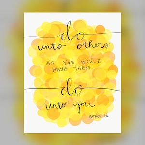 May include: A white print featuring the phrase "do unto others as you would have them do unto you" in black script. The text is set against a backdrop of yellow and orange circles. The text "Matthew 7:12" is at the bottom.