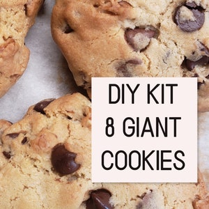 Pu&ograve; includere: Kit fai-da-te per preparare 8 biscotti giganti con gocce di cioccolato. L'immagine mostra tre grandi biscotti con gocce di cioccolato su una superficie bianca.