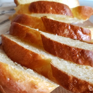 Puede incluir: Primer plano de una hogaza de pan rebanado. El pan es de color marr&oacute;n dorado y tiene una textura suave y esponjosa.