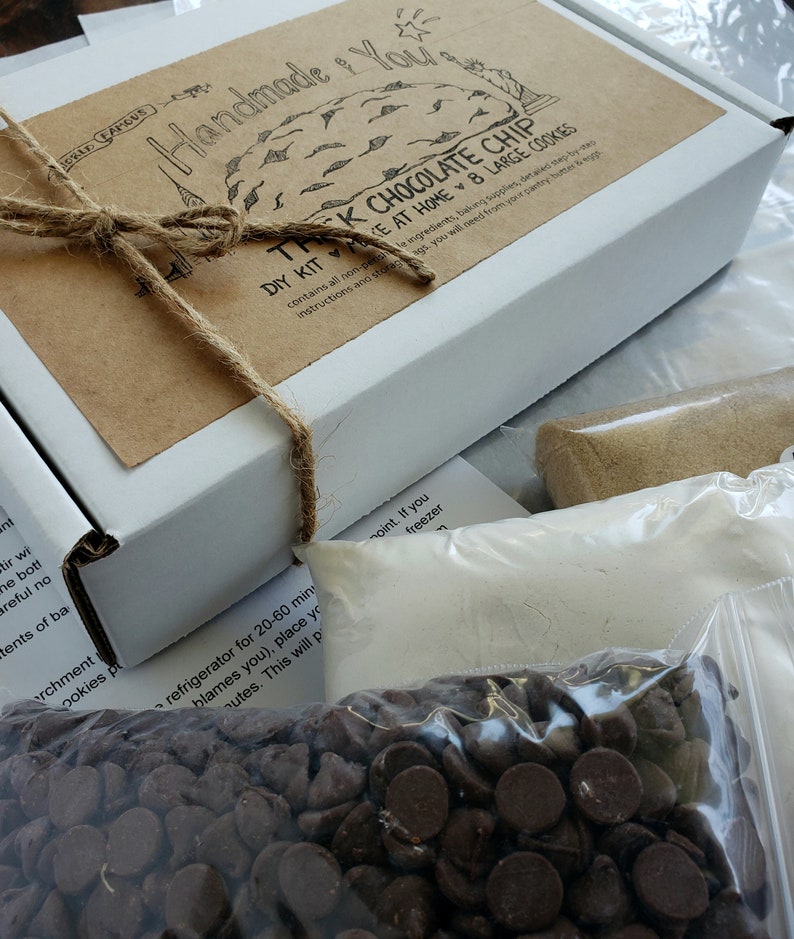 Pu&ograve; includere: Una scatola marrone con un'etichetta bianca che dice "Handmade for You" e "The Chocolate Chip DIY Kit - Make at Home 8 Large Cookies". La scatola &egrave; legata con uno spago e ha un sacchetto di gocce di cioccolato di fronte.