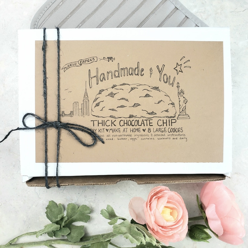 Pu&ograve; includere: Una scatola marrone con un'etichetta bianca che dice "World Famous Handmade & You" con un disegno di un biscotto al cioccolato e la Statua della Libert&agrave;. L'etichetta dice anche "Thick Chocolate Chip DIY Kit Make at Home 8 Large Cookies".