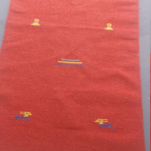 May include: A red rug with a fringe border and a geometric pattern of yellow and blue shapes.