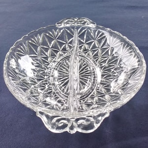 Könnte beinhalten: Eine durchsichtige Glasschüssel mit zwei Fächern, einem Diamantenmuster und verzierten Griffen.