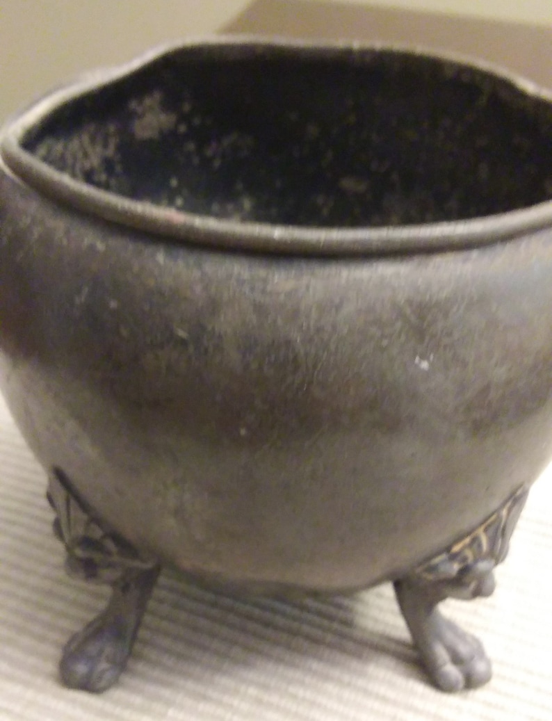 vintage small metal planter supported by four lion paw legs.