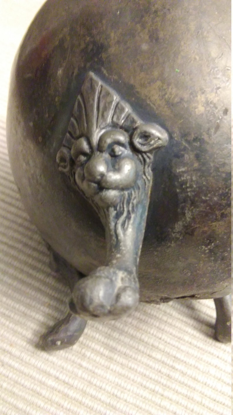 vintage small metal planter supported by four lion paw legs.