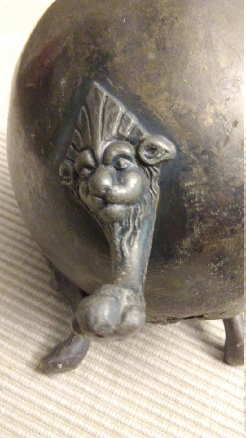 vintage small metal planter supported by four lion paw legs.