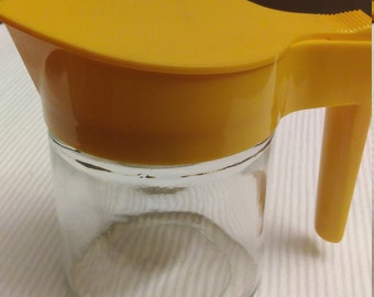 Syrup pourer by Gemco.  Glass with yellow plastic top, 70's.