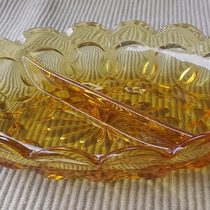 Könnte beinhalten: Eine geteilte Servierplatte aus bernsteinfarbenem Glas mit einem gewellten Rand und einem strukturierten, perligen Design.