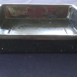 Może przedstawiać: Czarna prostokątna forma do pieczenia z kropkowanym białym wykończeniem. Forma ma prostokątny kształt i lekko uniesiony rant.