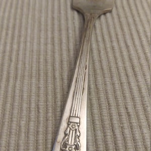 May include: A silver fork with an ornate handle. The handle has a floral design and a raised band.