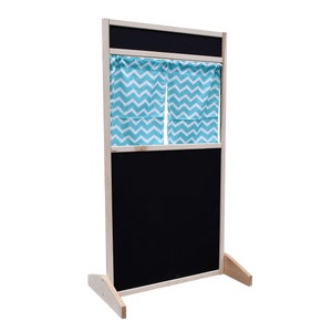 May include: A wooden puppet theater with a black chalkboard and a turquoise chevron patterned curtain. The theater has a wooden base with two legs.