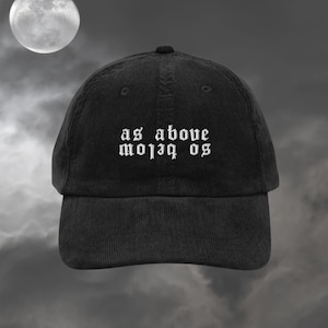 Peut inclure: Une casquette de baseball en velours côtelé noir avec une inscription brodée en blanc sur le devant. La ligne supérieure indique as above en police gothique, tandis que la ligne inférieure indique so below en police inversée et miroir.