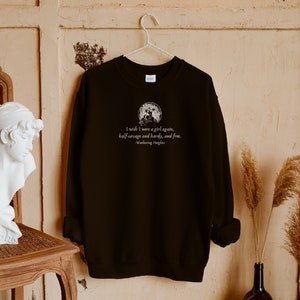 May include: Black sweatshirt with a white graphic print of a quote from the book "Wuthering Heights" by Emily Bront&euml;. The quote reads: "I wish I were a girl again, half-savage and hardy, and free."