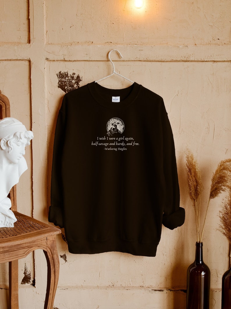 May include: Black sweatshirt with a white graphic print of a quote from the book "Wuthering Heights" by Emily Bront&euml;. The quote reads: "I wish I were a girl again, half-savage and hardy, and free."