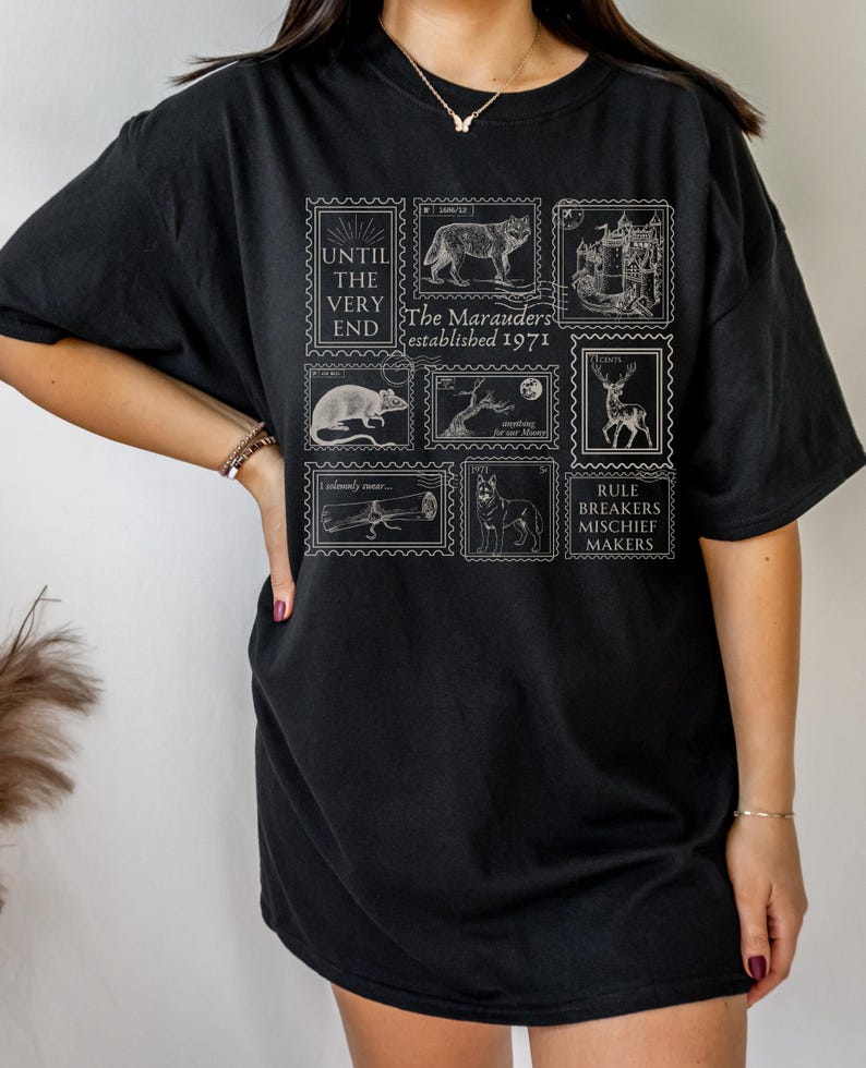 May include: Black t-shirt with a white graphic print of a series of stamps featuring images of a wolf, a castle, a rat, a tree, a deer, a wand, and a dog. The stamps have text that reads "Until the very end", "The Marauders established 1971", "I solemnly swear...", and "Rule Breakers Mischief Makers".