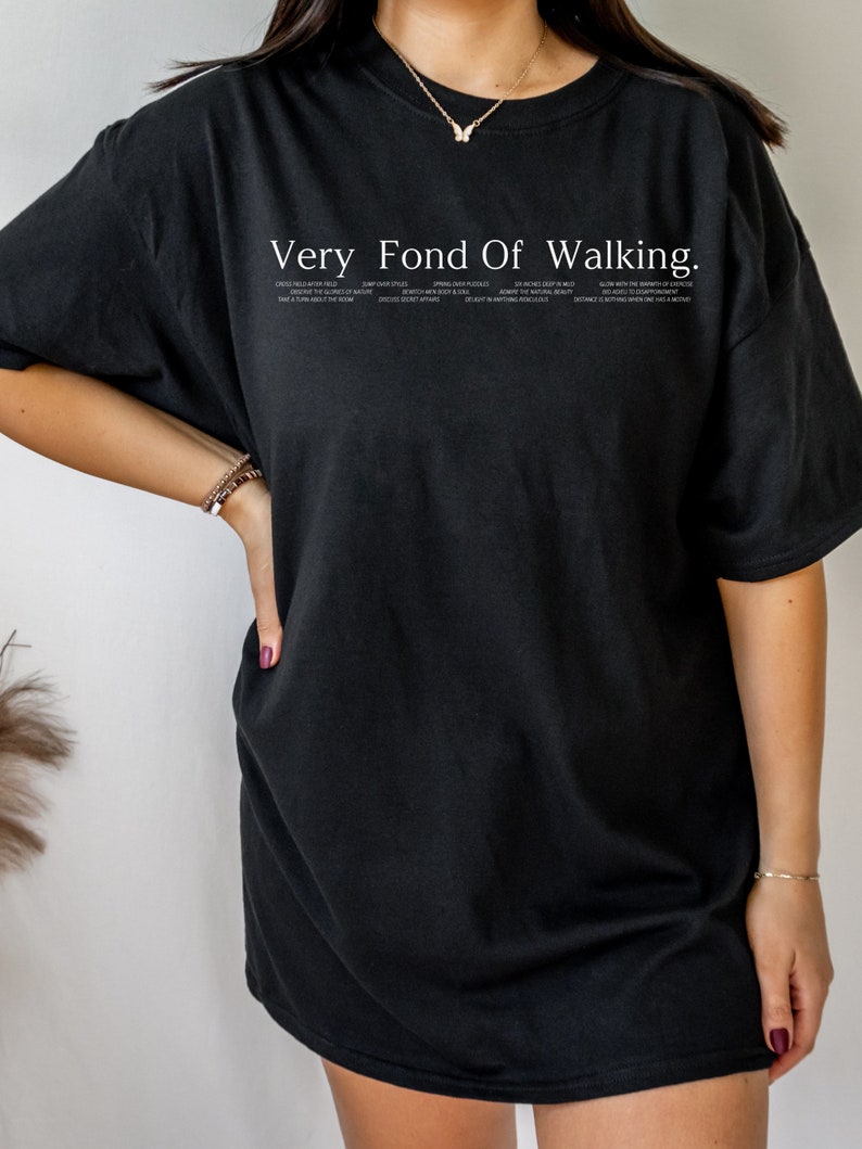 May include: Black oversized t-shirt with the text "Very Fond Of Walking." The text is in white and includes a list of phrases about walking.
