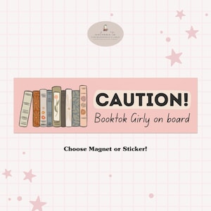 May include: A rectangular pink sign with the text "CAUTION! Booktok Girly on board" and a row of illustrated books. The sign also says "Choose Magnet or Sticker!" in black text.