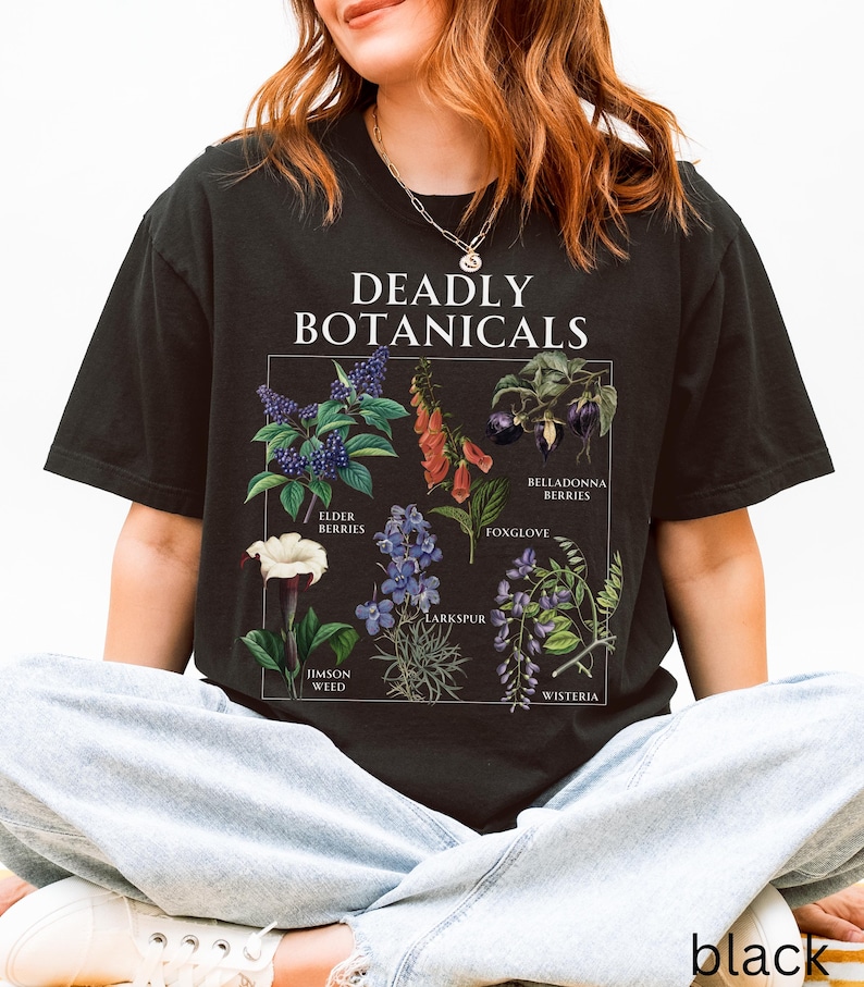 May include: Black t-shirt featuring the text "DEADLY BOTANICALS" above a botanical illustration of various plants, including Elderberries, Foxglove, and Jimson Weed. The shirt is a comfortable, casual style.