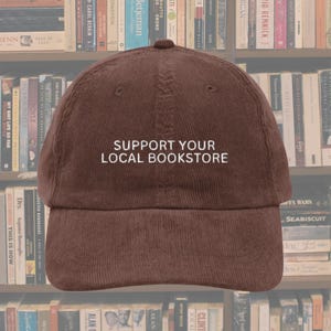 May include: A brown corduroy baseball cap with the text "Support Your Local Bookstore" embroidered on the front.