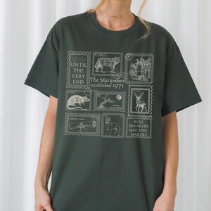 May include: A dark green t-shirt with a white graphic print of a series of stamps featuring various animals and the text "The Marauders established 1971" and "Until the very end".