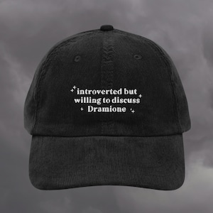 May include: Black corduroy baseball cap with white embroidered text: "introverted but willing to discuss Dramione".