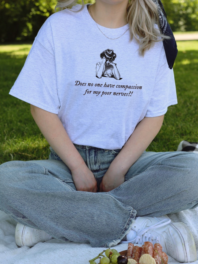 K&ouml;nnte beinhalten: Ein wei&szlig;es T-Shirt mit einer Schwarzwei&szlig;illustration einer Frau mit dem Text "Does no one have compassion for my poor nerves?!"