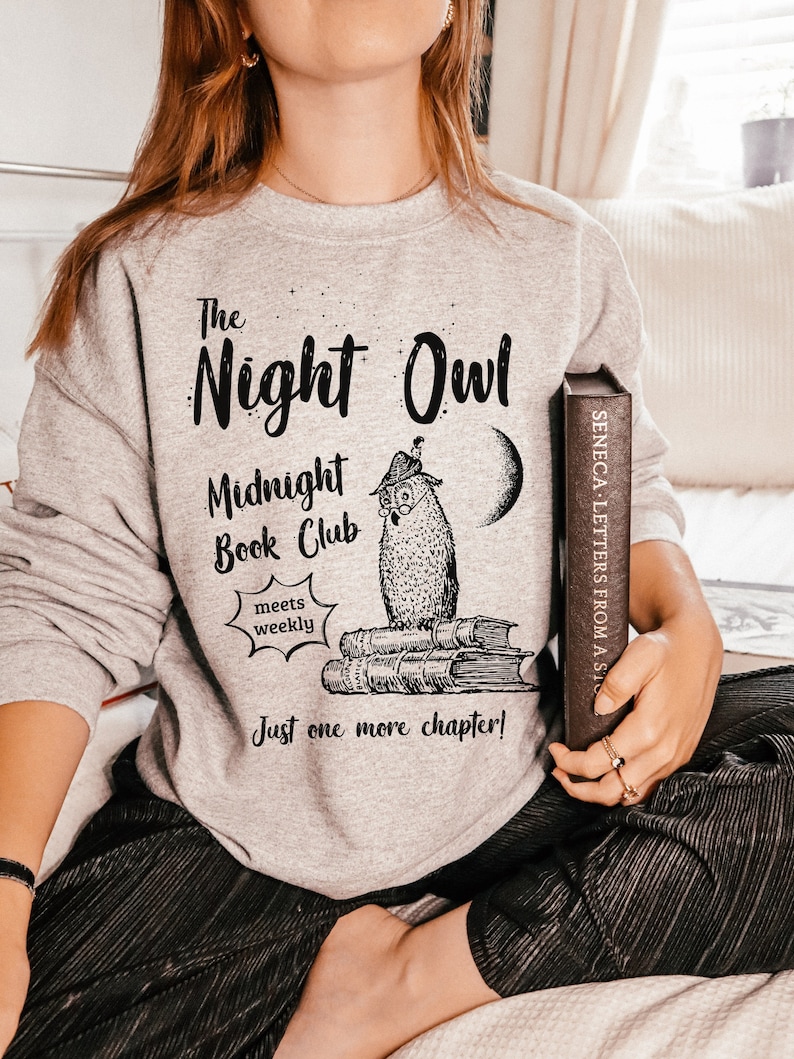 May include: Gray sweatshirt with a black graphic of an owl reading a book. The text on the sweatshirt reads "The Night Owl Midnight Book Club meets weekly Just one more chapter!"