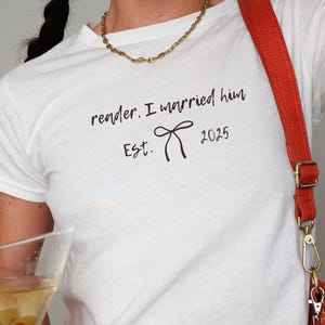 May include: White t-shirt with the text "reader, I married him Est. 2025" and a small bow graphic.