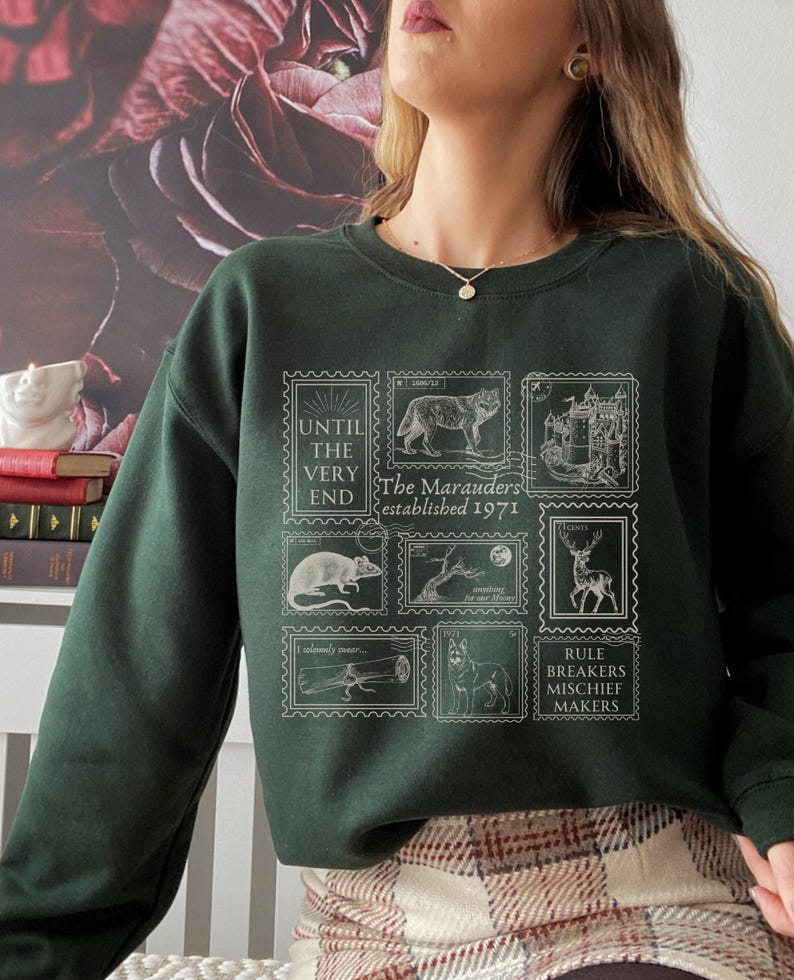 K&ouml;nnte beinhalten: Ein dunkelgr&uuml;ner Pullover mit einem wei&szlig;en Grafikdruck von Briefmarken mit Illustrationen eines Wolfes, einer Ratte, eines Hirsches, eines Baumes, eines Schlosses und eines Hundes. Die Briefmarken tragen den Text "The Marauders established 1971", "Until the very end", "I solemnly swear", "Mischief managed", "Moony", "Wormtail", "Padfoot", "Prongs" und "Rule breakers mischief makers".