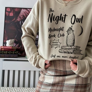 May include: A beige sweatshirt with the text "The Night Owl Midnight Book Club meets weekly Just one more chapter!" and a black and white illustration of an owl sitting on a stack of books.