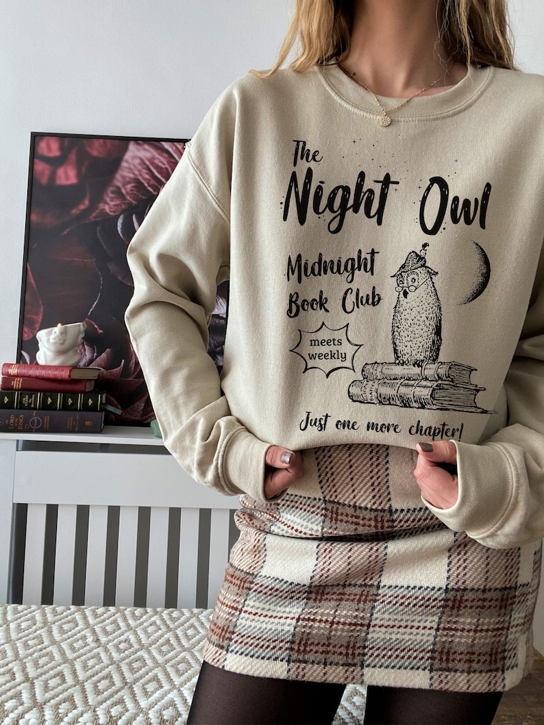 May include: A beige sweatshirt with the text "The Night Owl Midnight Book Club meets weekly Just one more chapter!" and a black and white illustration of an owl sitting on a stack of books.
