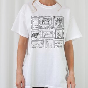 May include: White t-shirt with a black graphic print of stamps featuring illustrations of animals and the text "Until the very end, The Marauders established 1971, Rule Breakers Mischief Makers".