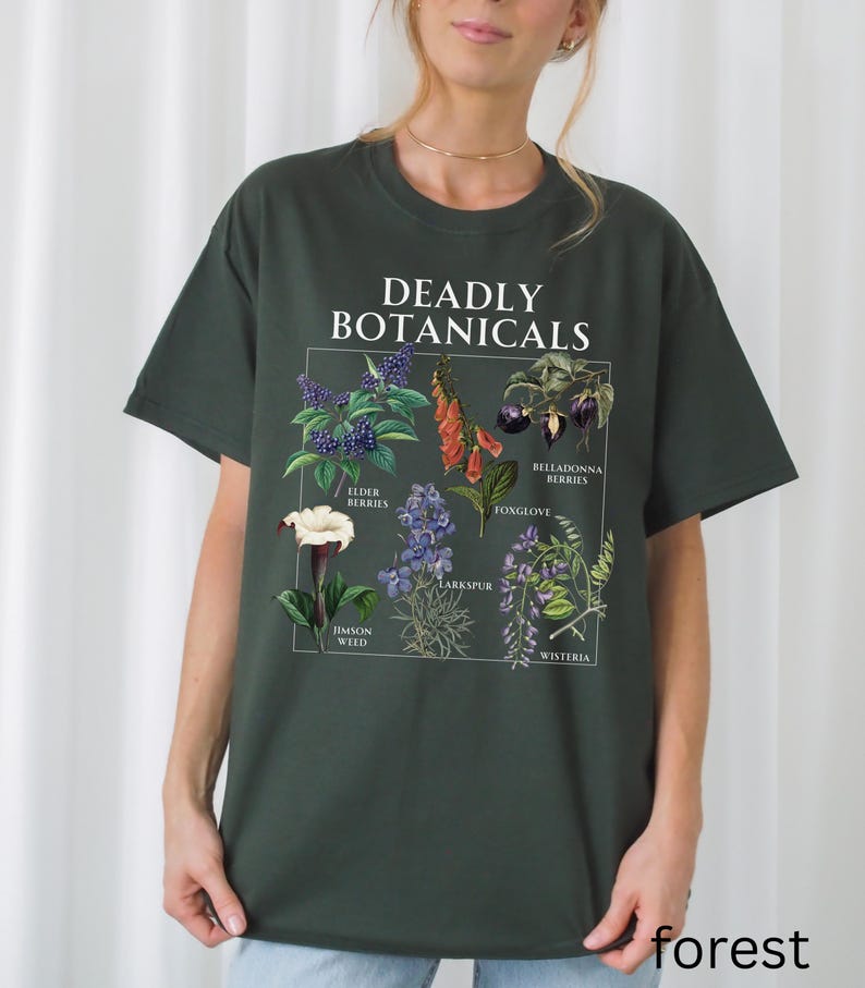 May include: Dark green t-shirt featuring a botanical illustration with the text "DEADLY BOTANICALS." The graphic includes images of elderberries, foxglove, and other plants. The word "forest" is printed at the bottom of the shirt.