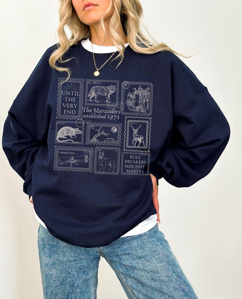 K&ouml;nnte beinhalten: Ein marineblauer Pullover mit einem grafischen Druck von Briefmarken mit verschiedenen Tieren und dem Text "The Marauders established 1971" und "Rule Breakers Mischief Makers".